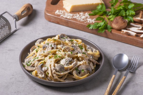 A delicious plate of fettuccine alfredo with mushrooms and a sprinkle of parsley.