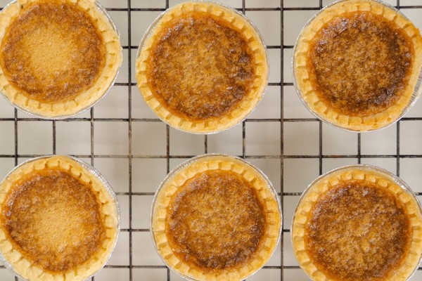 Golden brown butter tarts cooling on a wire rack, showcasing their flaky crust and caramelized filling