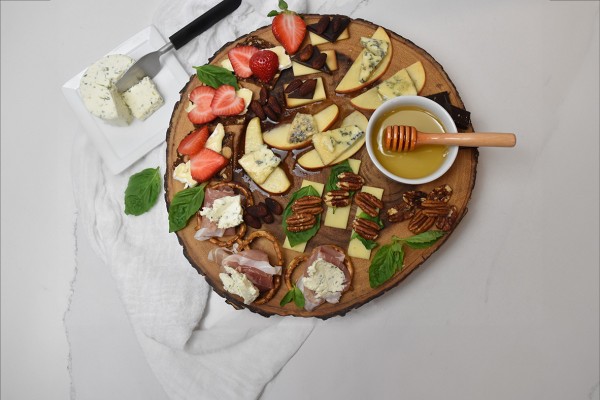 Assortment of cheese, crackers, fresh fruit, nuts, and honey artfully arranged for elegant appetizer pairings.