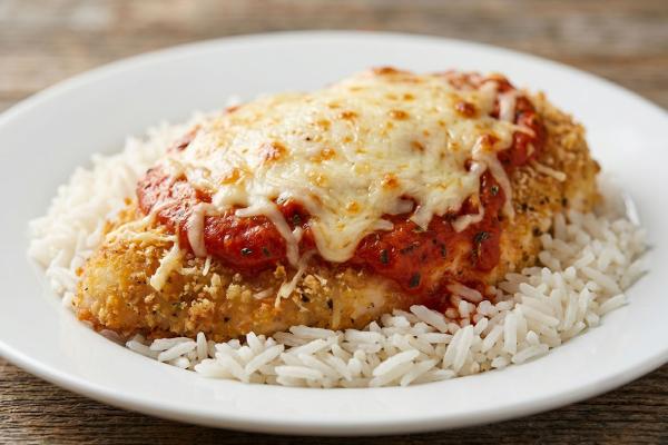 Succulent Chicken Parmesan with a crispy golden coating, smothered in tomato sauce, atop a bed of wild rice blend