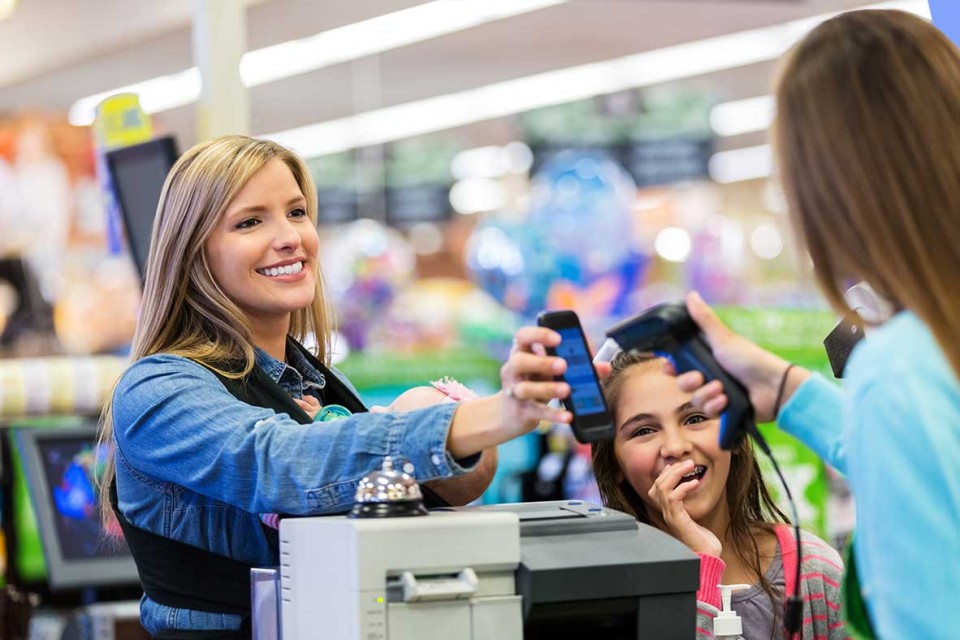 Woman paying for groceries using coupon app on phone. 