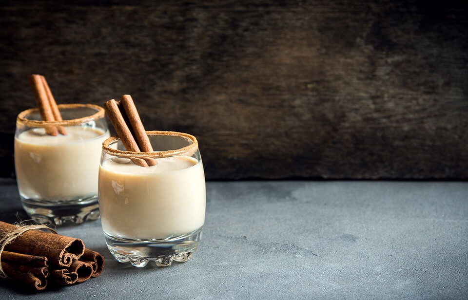 Eggnog in glasses with cinnamon sticks 