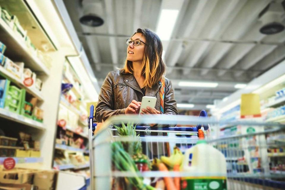 Woman grocery shopping with her grocery list on her phone. 
