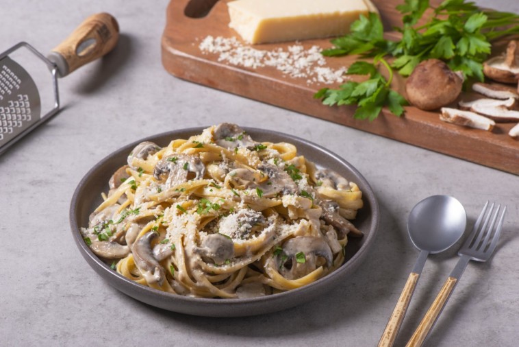 A delicious plate of fettuccine alfredo with mushrooms and a sprinkle of parsley.