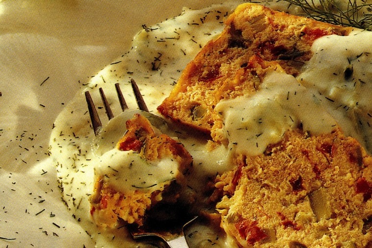 A beautiful slice of salmon loaf with a side of creamy dill sauce.